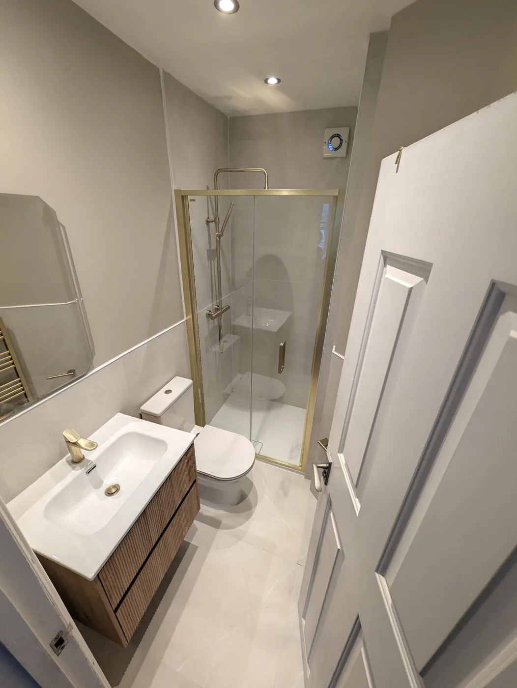 Completed compact shower room with brushed brass fittings and floating vanity
