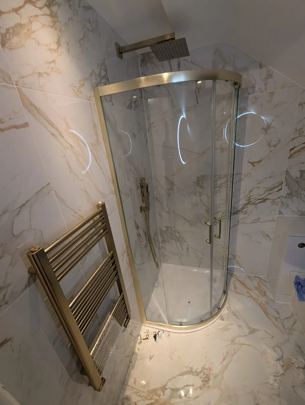 Marble-effect shower room with brushed metal enclosure and heated towel rail